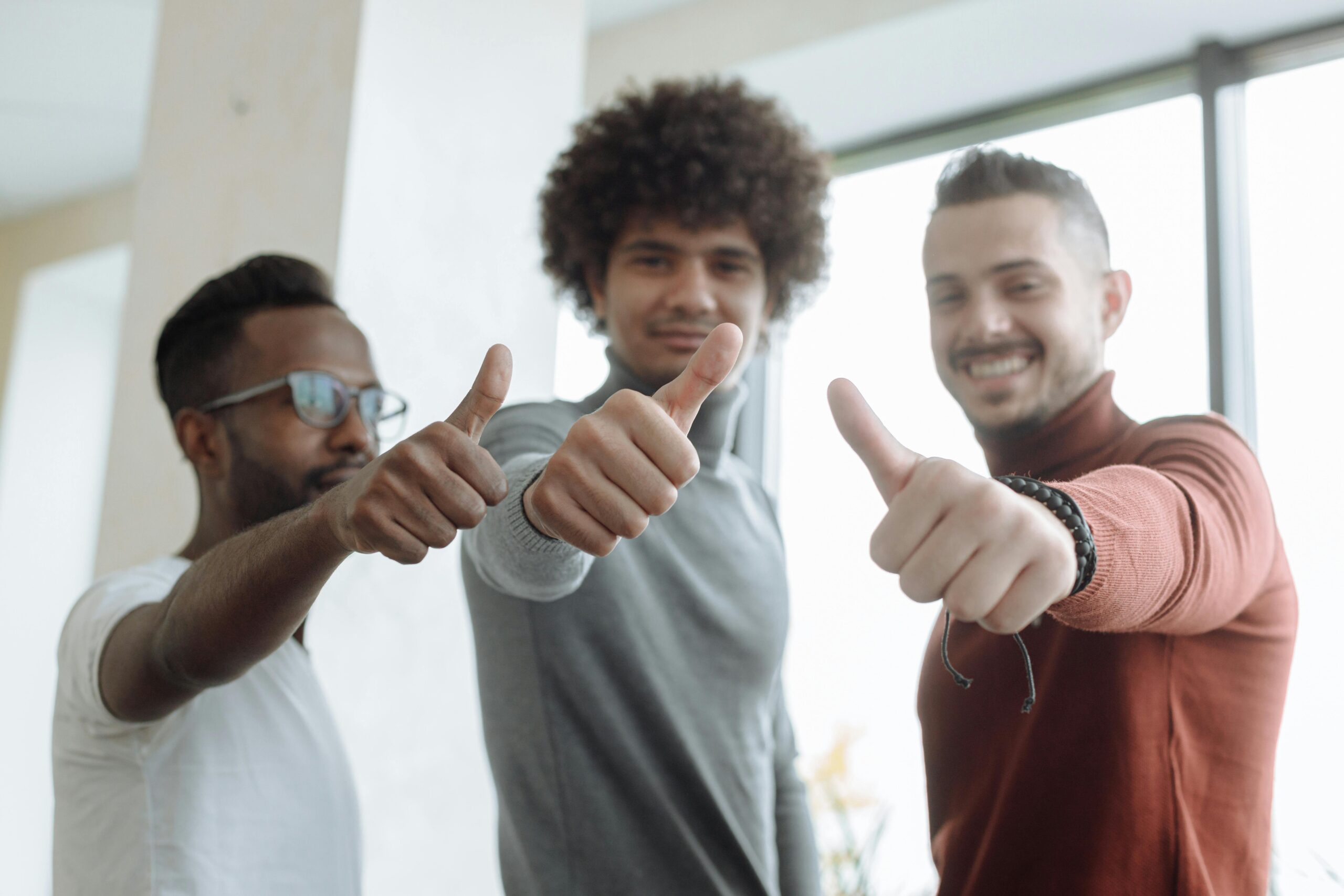 Three smiling professionals giving a thumbs-up gesture in a bright office—representing positive outcomes, client satisfaction, and successful partnerships with Fran & Hill.